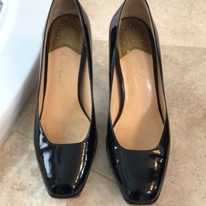 Square black patent leather pumps.